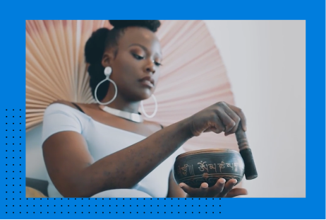 A black woman using a singing bowl and looking into it with deep concentration.